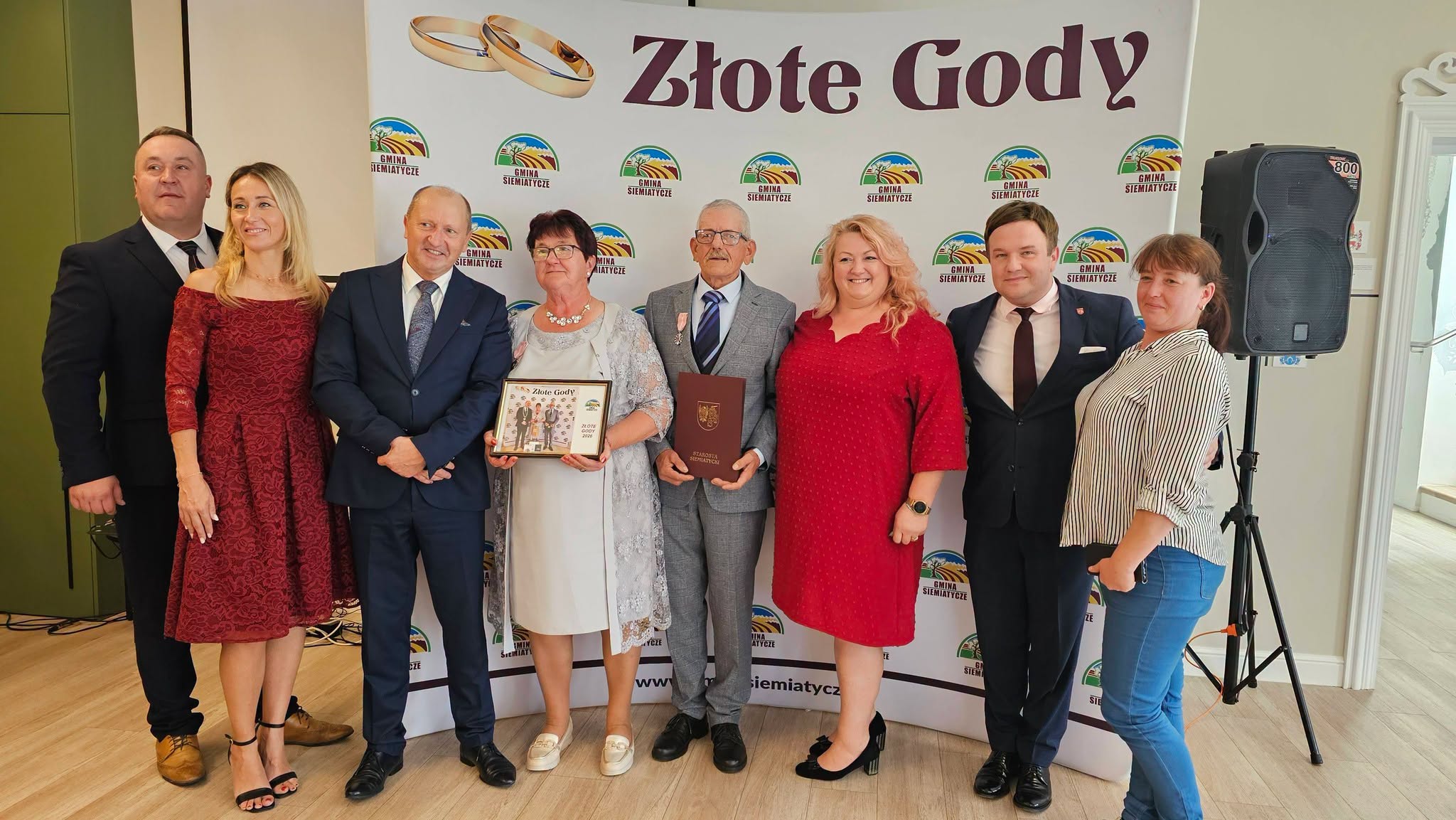 Grupa osób pozuje razem przed transparentem z napisem „Złote Gody”.