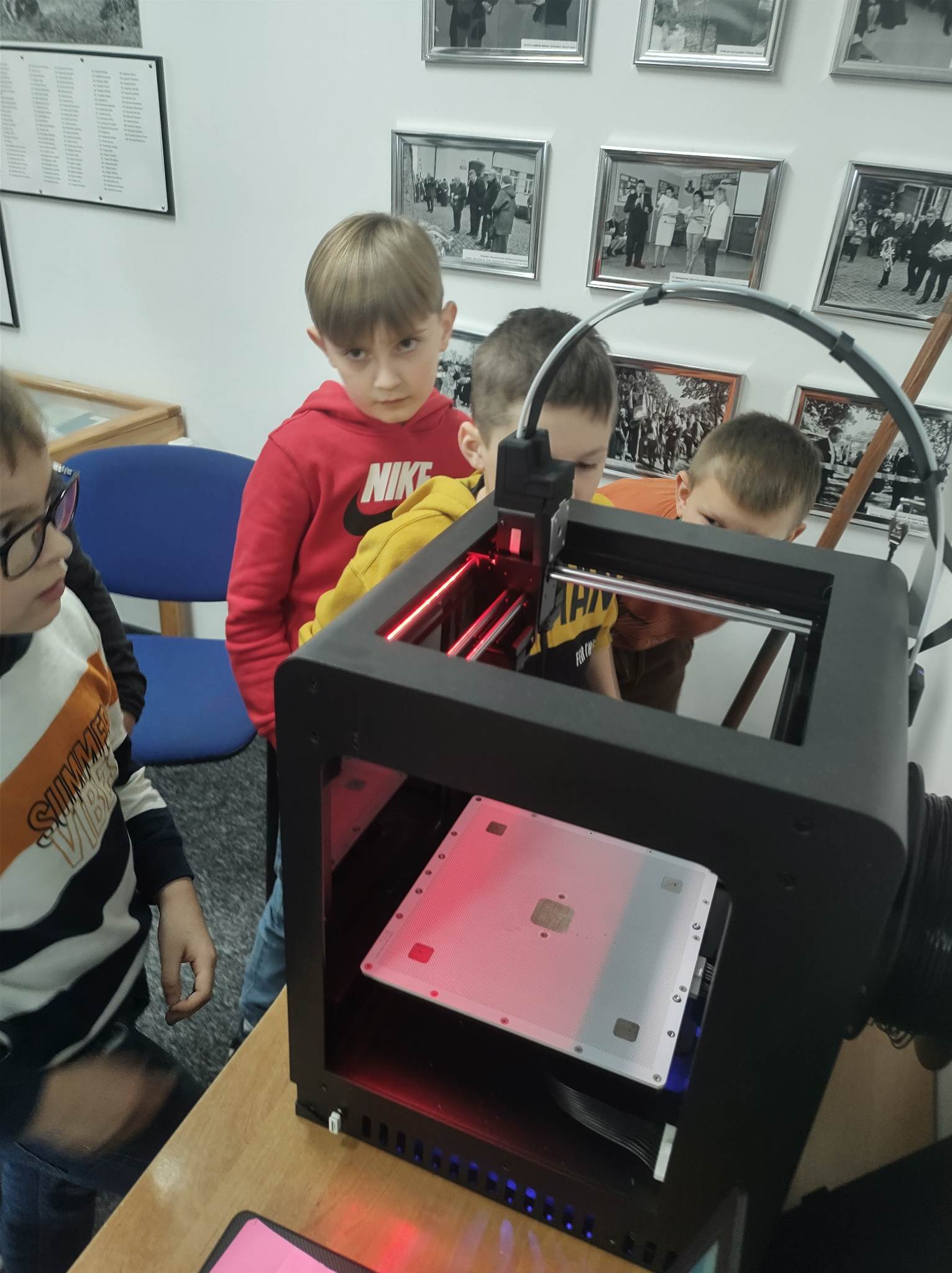 Uczniowie przyglądają sie pracy drukarki 3D