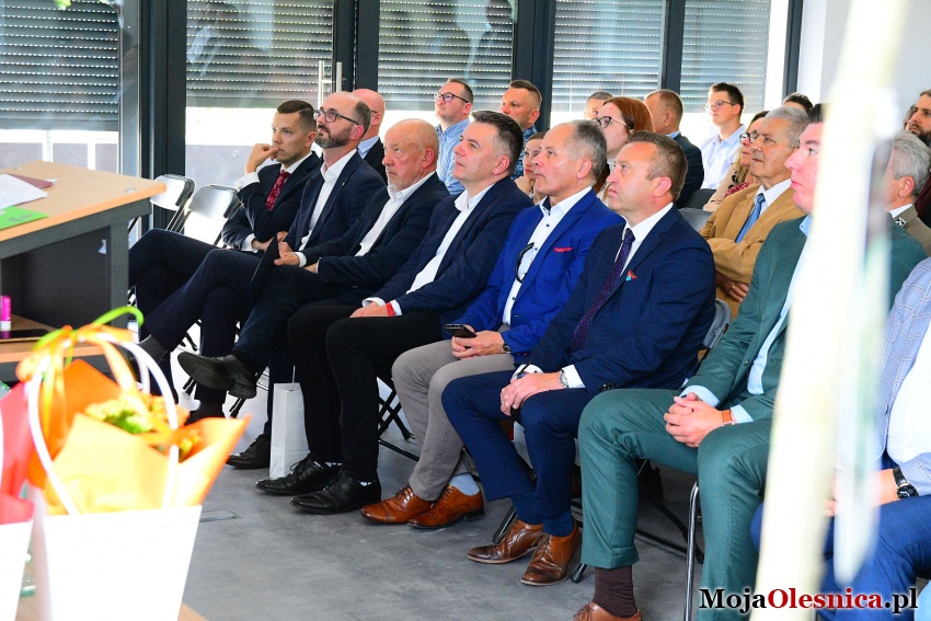 Uczestnicy wydarzenia siedzą na krzesłach w sali konferencyjnej i patrzą w kierunku przemawiających