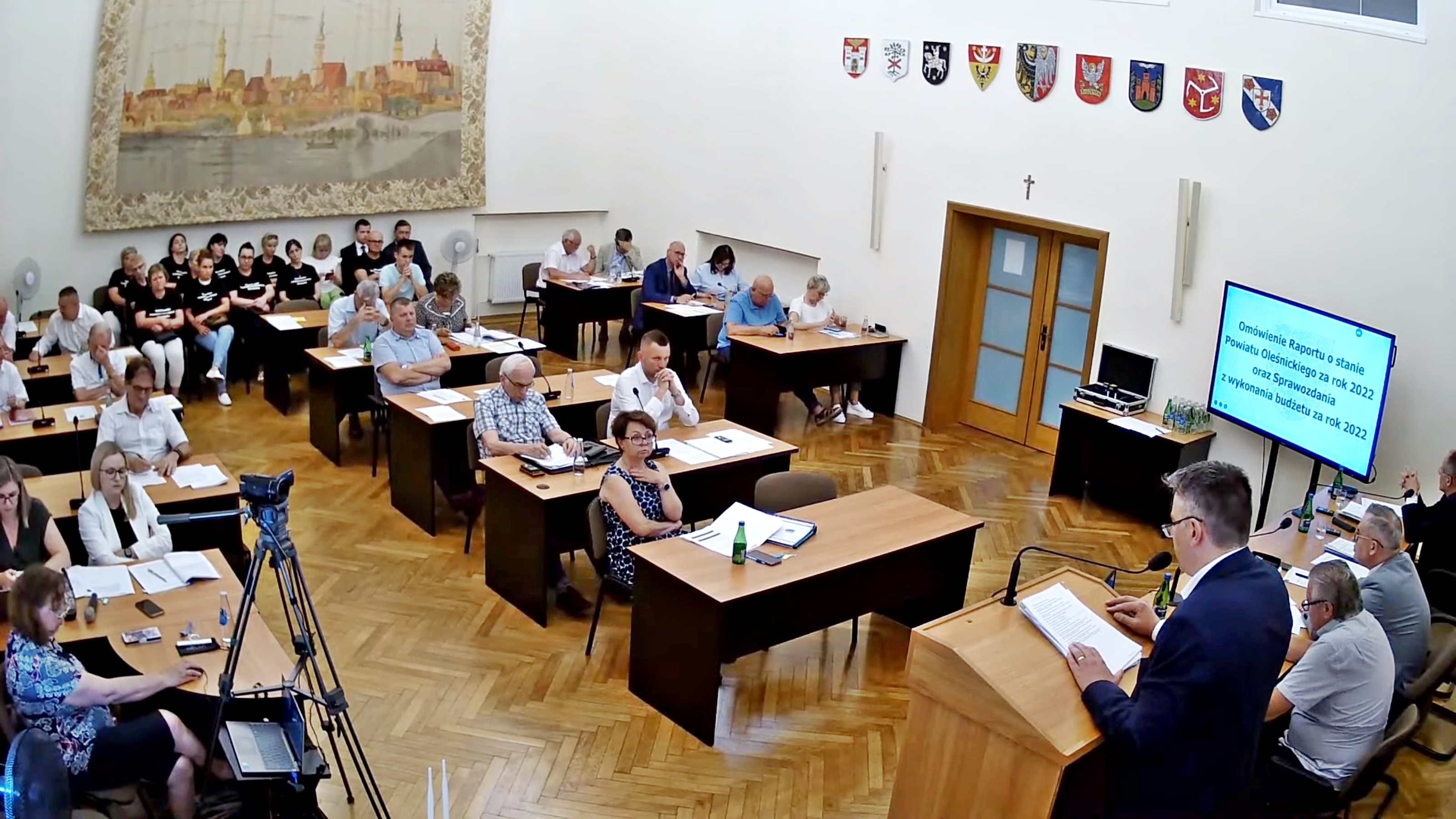 Powiatowi radni w sali obrad słuchają wystąpienia starosty