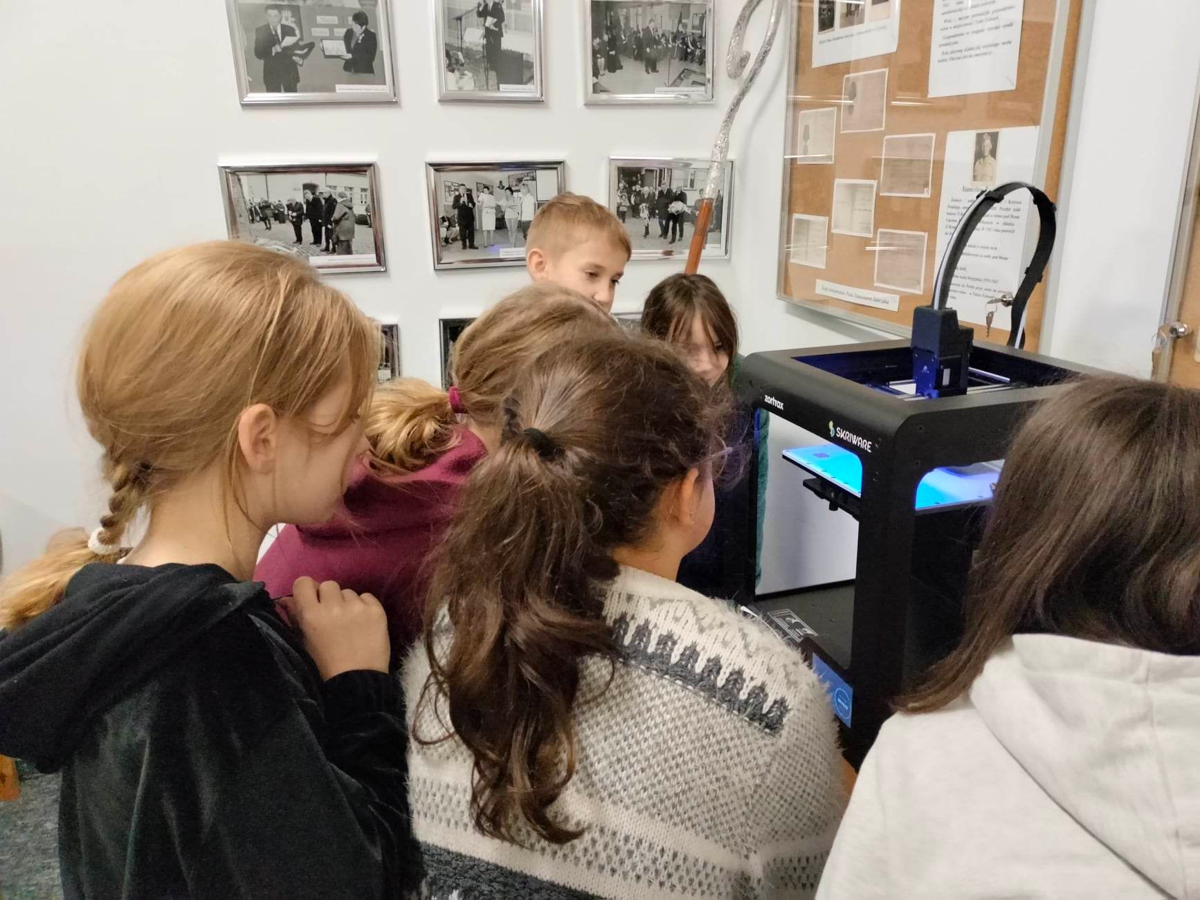 Dzieci przyglądają się pracy drukarki 3D.