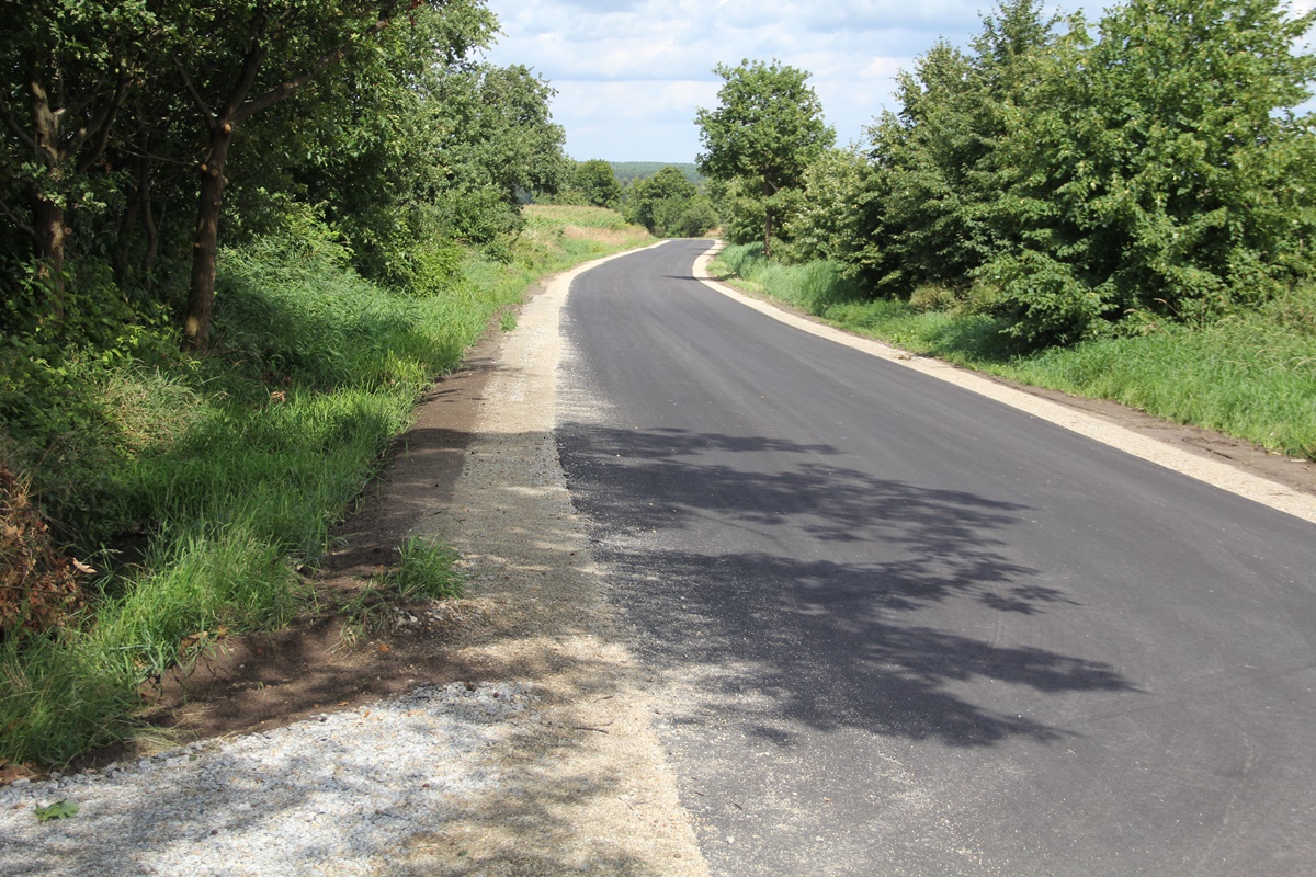 Nowy asfalt na drodze ciągnie się kilometrami. Po obu stronach białe pobocza, w tle drzewa, łąki, lasy