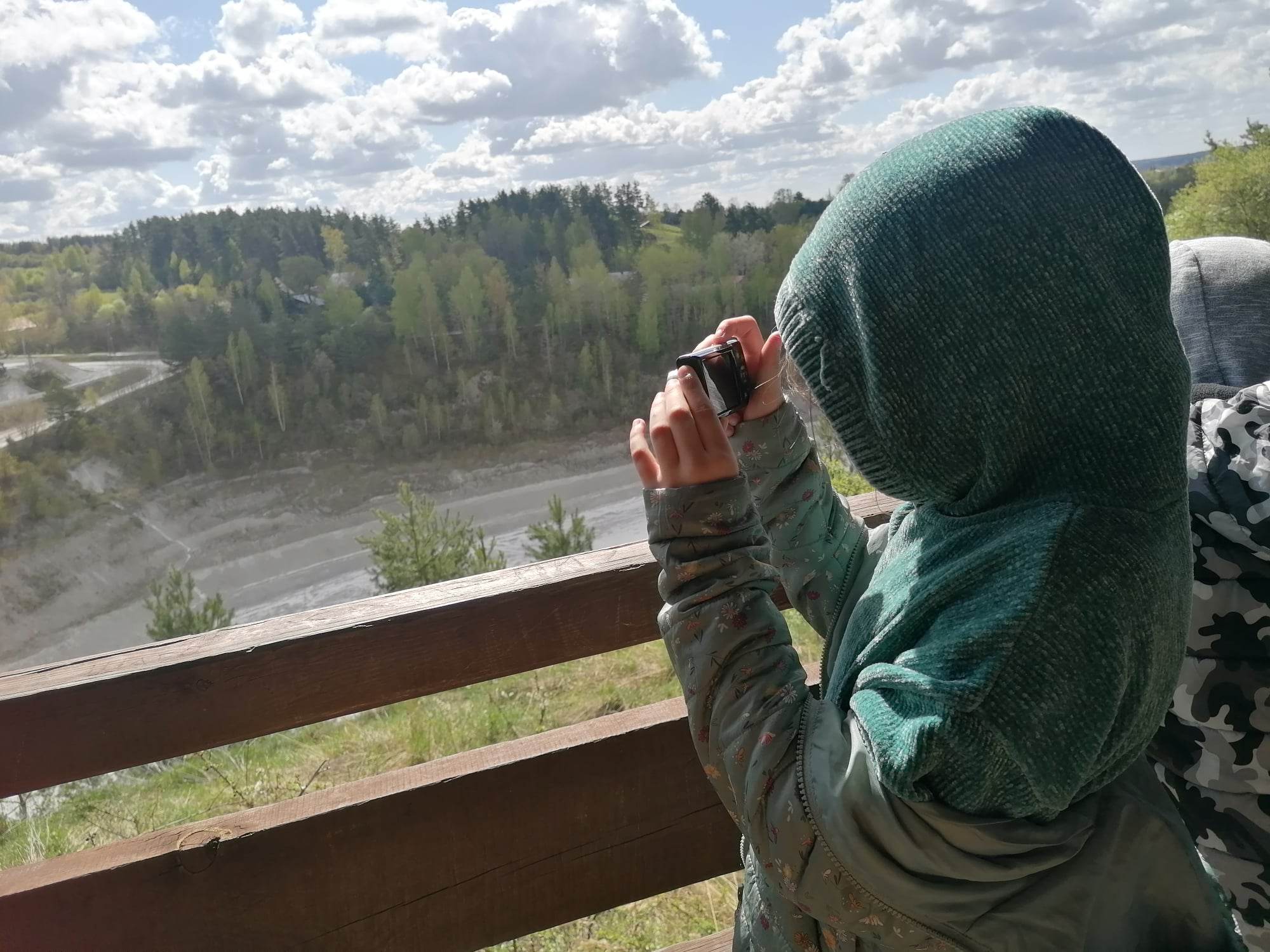 ​Dziewczynka ubrana w zieloną bluzę z kapturem wykonuje zdjęcie Kopalni Kredy w Mielniku.