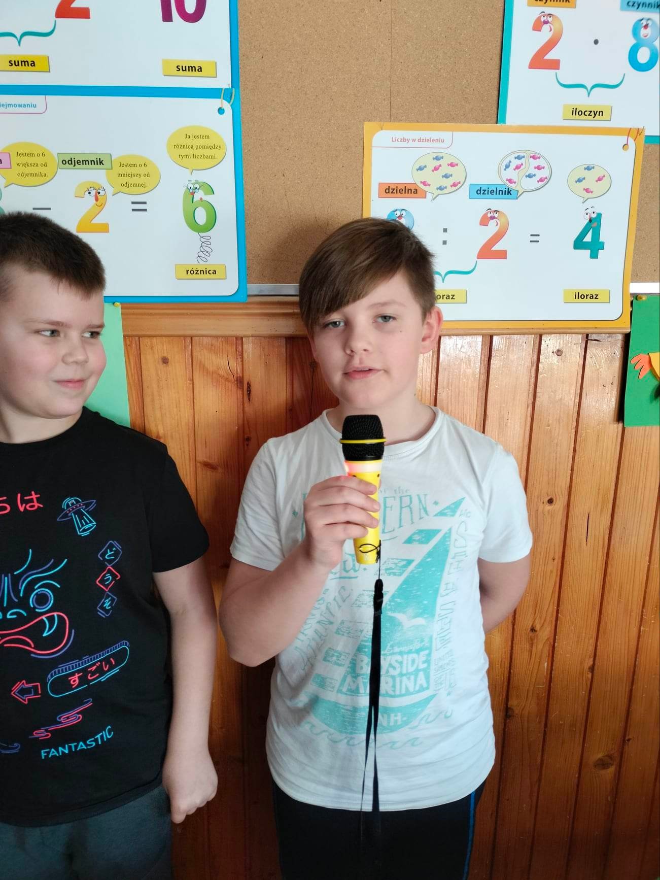 Chłopiec trzyma w dłoni żółty mikrofon do którego mówi.