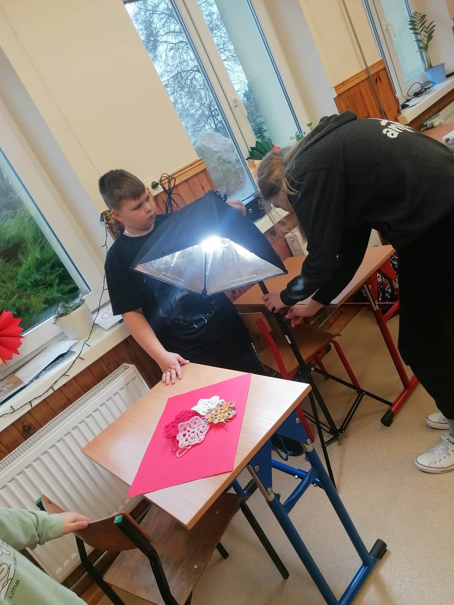 Uczennica ustawia lampę fotograficzną.