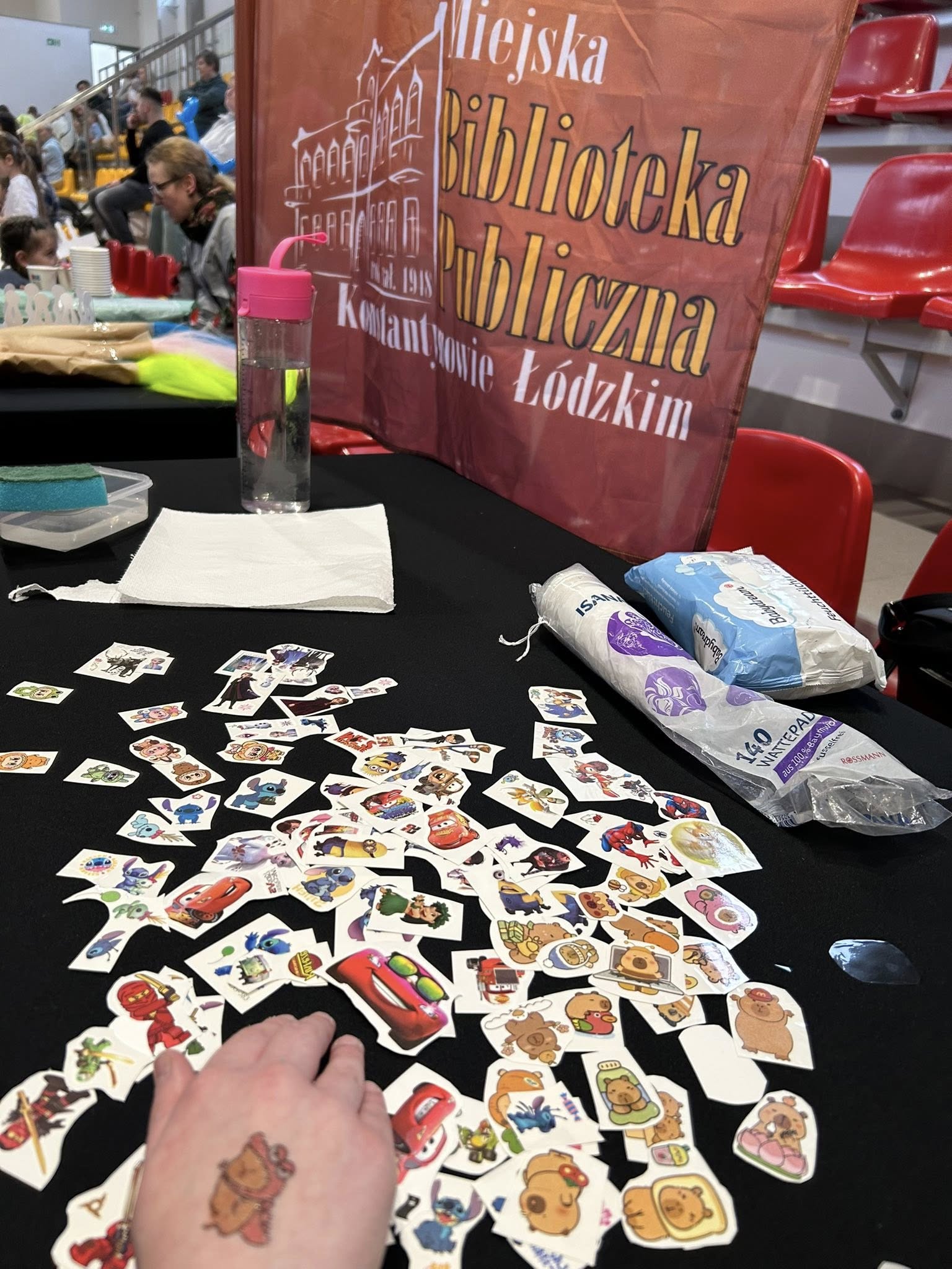 Zdjęcie przedstawia stanowisko przyklejanych tatuaży Miejskiej Biblioteki Publicznej w Konstantynowie Łódzkim w hali Fun Lab podczas imprezy zakończenie ferii 2026.