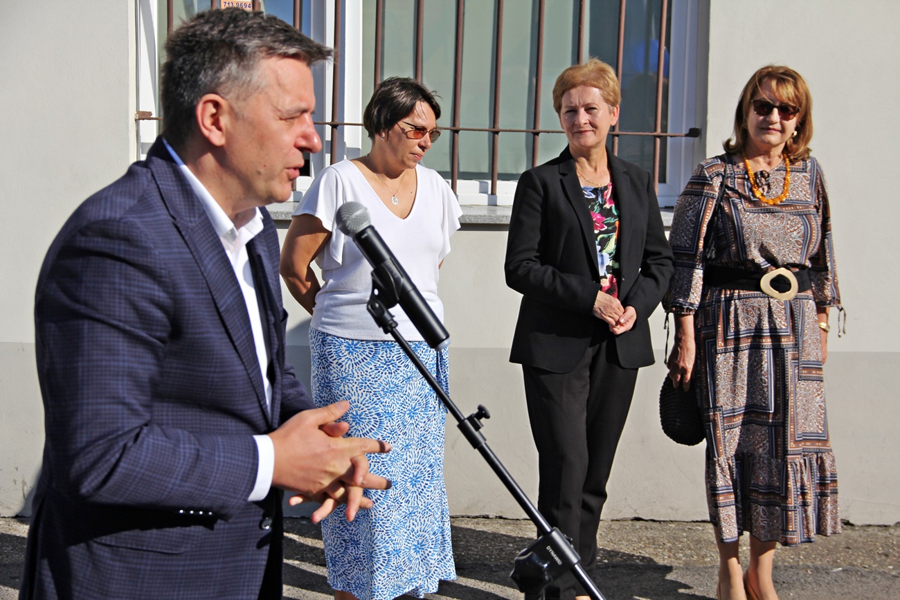 Starosta Sławomir Kapica stoi przed mikrofonem, w tle za nim stoją obok siebie: dyrektor szkoły, naczelniczka i radna powiatowa