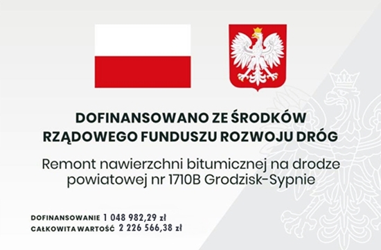 Baner z flagą Polski, herbem i tekstem dotyczącym lokalnego projektu inwestycyjnego. Tekst transkrypcji: DOFINANSOWANO ZE ŚRODKÓW RZĄDOWEGO FUNDUSZU ROZWOJU DRÓG Remont nawierzchni bitumicznej na drodze powiatowej nr 1710B Grodzisk-Sypnie DOFINANSOWANIE 1 048 982,29 zł CAŁKOWITA WARTOŚĆ 2 226 566,38 zł