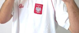 Szymon Członka w białej koszulce z herbem Polski z postawą z rękami w górze i zaciśniętymi pięściami