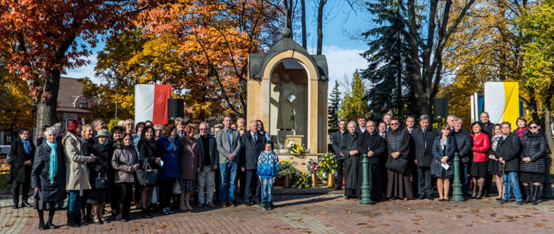 Zdjęcie grupowe osób uczestniczących w uroczystościach św. Jana Pawła II w Kalwarii Zebrzydowskiej. W centrum zdjęcia pomnik Św. Jana Pawła II. 