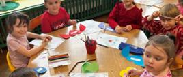 Dzieci siedzą przy stolikach, tworzą kartki walentynkowe