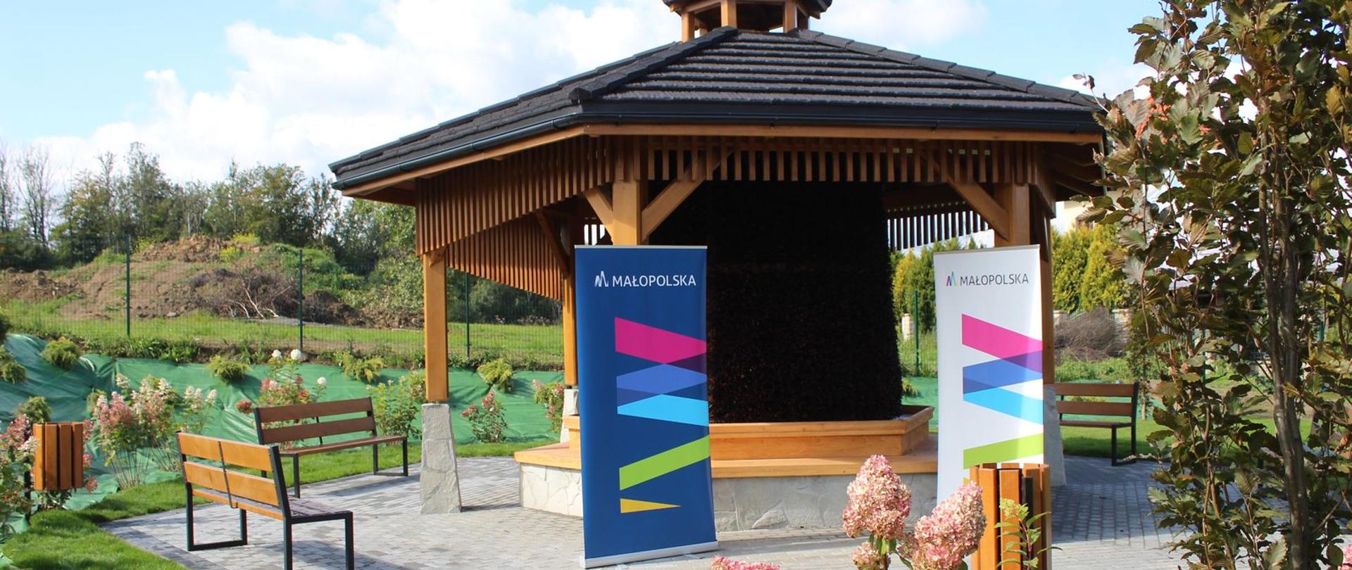 Na zdjęciu w centralnym miejscu tężnia solankowa, po prawej kwiaty i krzewy. 