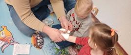 Nauka pierwszej pomocy - ratownik medyczny pokazuje dzieciom, jak opatrzyć ranę