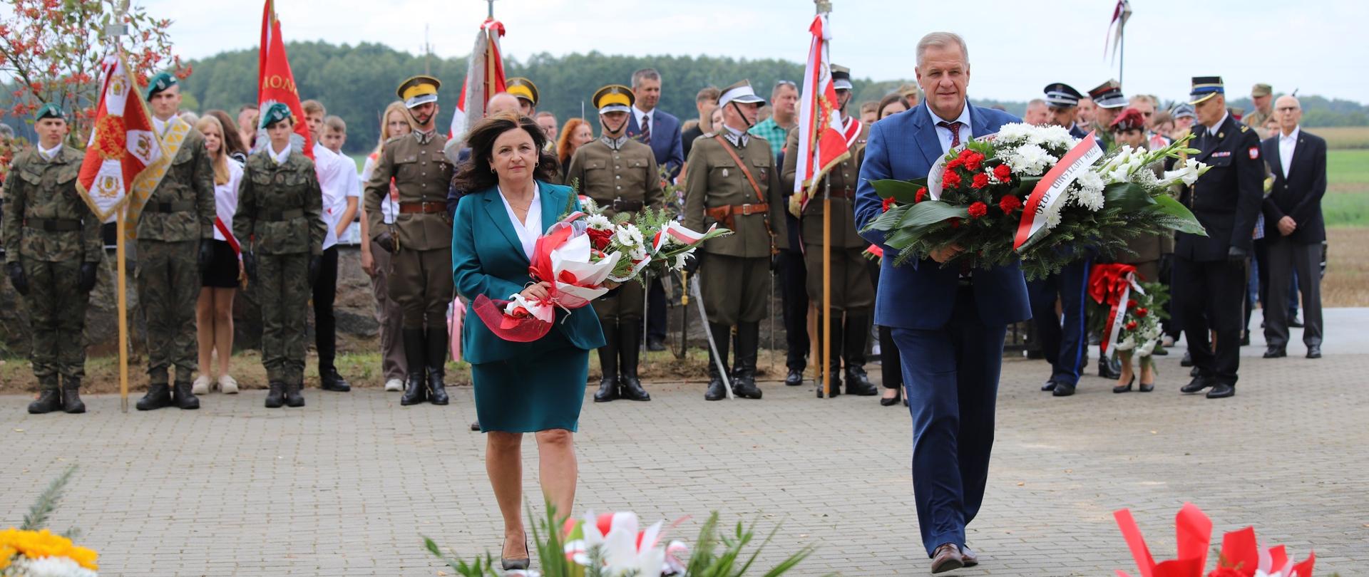 Starosta bielski Sławomir Jerzy Snarski i senator RP Anna Bogucka składają wiązanki pod pomnikiem bitwy pod Olszewem (fot. Gminny Ośrodek Upowszechniania Kultury im Anny Dernowskiej w Kalnicy )