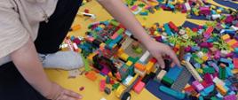 Dzieci w trakcie zabawy klockami lego - układają poszczególne elementy, pozują do zdjęć