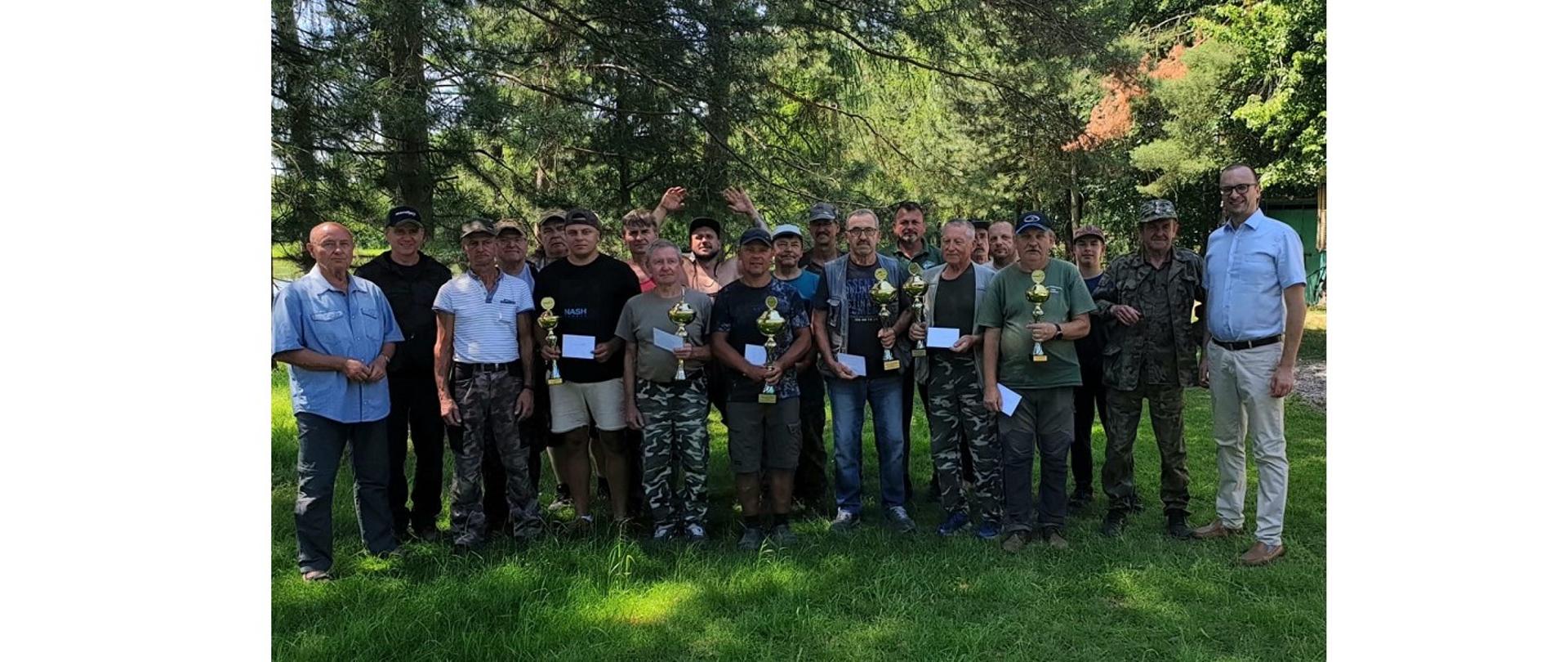 Finaliści zawodów w towarzystwie Wójta Grzegorza Sikorskiego, Prezesa Koła PZW Jana Cieślara oraz innych członków koła. Zdjęcie wykonane na terenie łowiska w Pogwizdowie