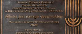 Zdjęcie przedstawia mosiężną tablicę, na której znajdują się napisy w języku polskim oraz jidysz. Polski napis głosi: "Pamięci Żydów z Kraśnika - obywateli polskich, zamordowanych przez Niemców. W 80. rocznicę Akcji Reinhardt (1942-1943). Pamięć jest naszym obowiązkiem - Marszałek Województwa Lubelskiego 2023".