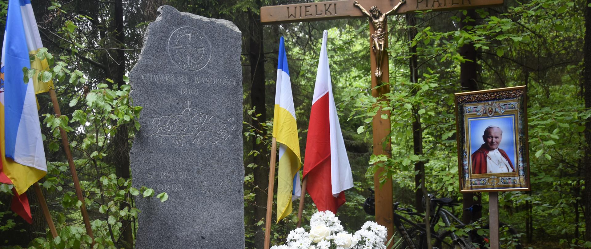 Pomnik na Rabskiej Górze, flagi: papieska, maryjna, polski. Obraz Jana Pawła II 