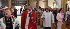 Moment poświęcenia wiernych i palm Wielkanocnych. Ksiądz wraz z kościelnym przechodzą przez kościół pomiędzy wiernymi siedzącymi przy ławkach.