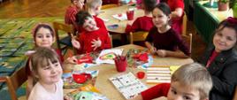 Dzieci siedzą przy stolikach, tworzą kartki walentynkowe