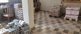 Palety z żywnością ułożone w sali osp remizy. Na paletach znajdują się makaron, dżem, sałatka w słoiku oraz pasztet.