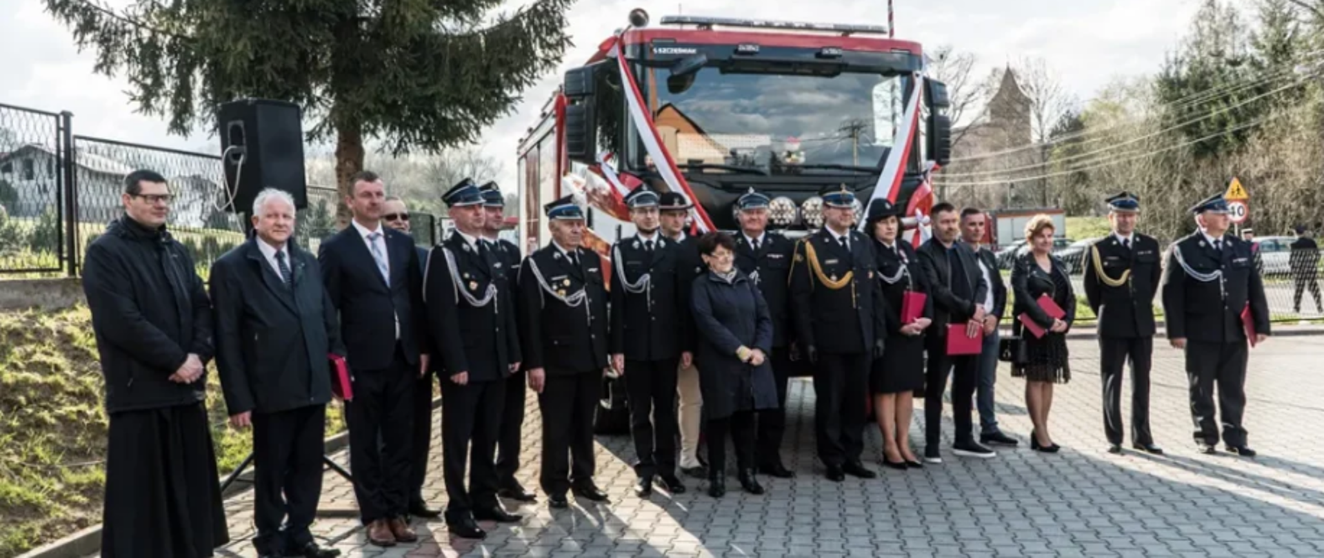 Pamiątkowa fotografia na tle wozu strażackiego.