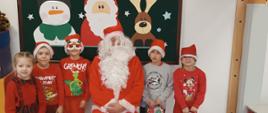 Wizyta św. Mikołaja - dzieci pozują do zdjęcia z Mikołajem