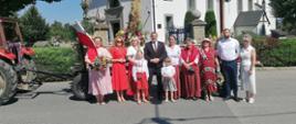 Grupa mieszkańców w strojach regionalnych i odświętnych pozuje przed kościołem w Rabie Wyżnej