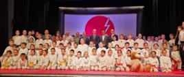 Zawodnicy Klubu Karate Tradycyjnego Chidori ustawieni na scenie Centrum Kultury i Promocji w Kraśniku. Po stronie prawej stoi trener i jednocześnie prezes klubu Marek Bury. Pośrodku karateków stoją zaproszeni gości.