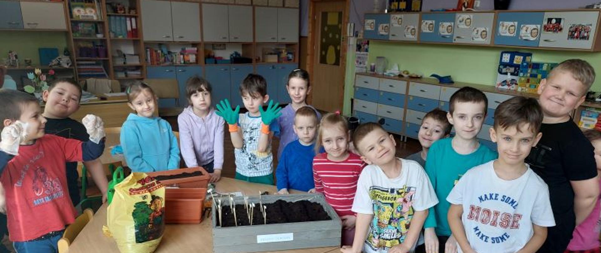 Dzieci prezentują efekty pracy - wspólnie założyły ogród, pozują przy przygotowanych przez siebie doniczkach