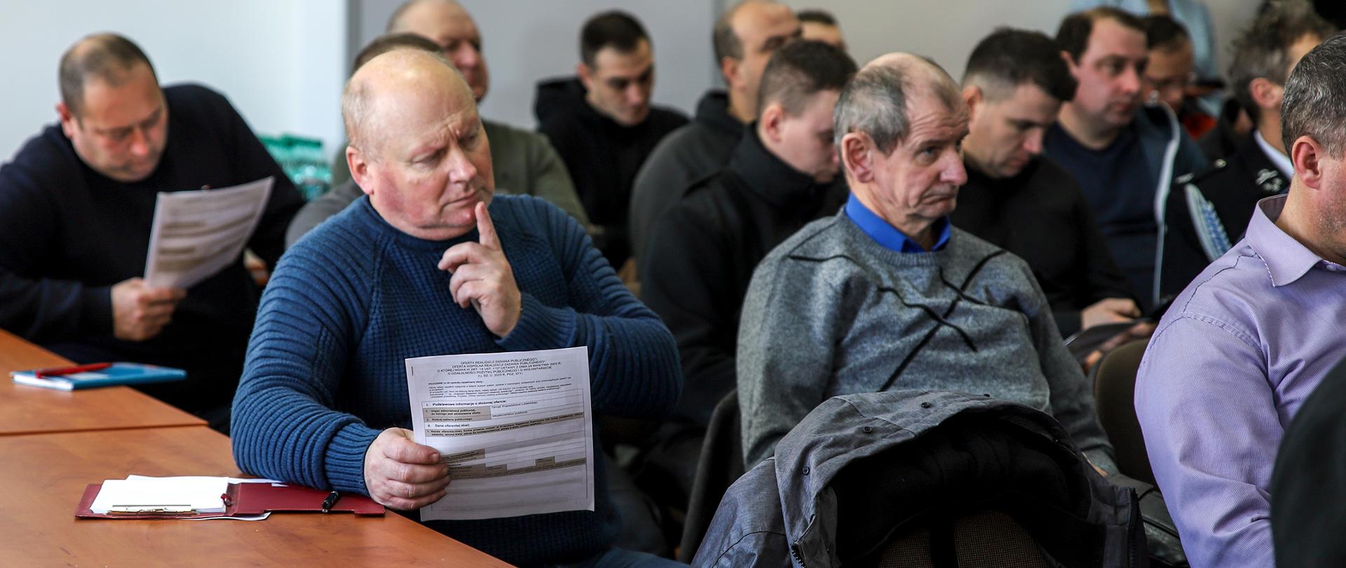 Na zdjęciu uczestnicy spotkania informacyjnego, którzy trzymają w dłoniach przykładowe wnioski o dofinansowanie.