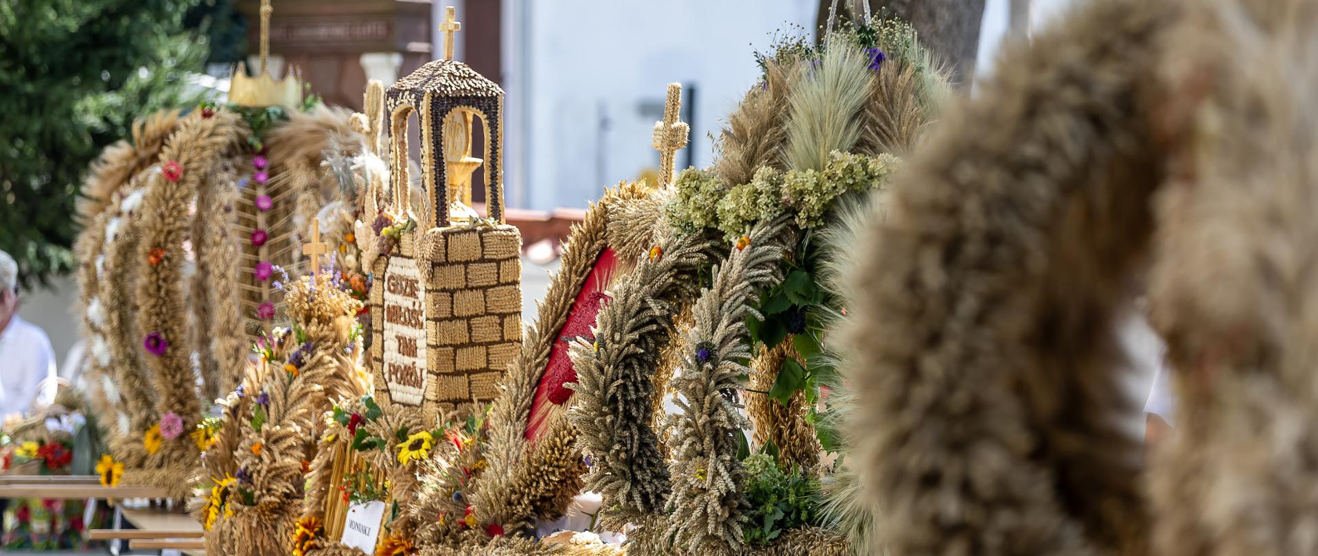 Fotografia wieńców dożynkowych wykonanych ze zbóż, kwiatów i ziół. 