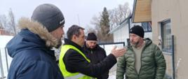 Czterej mężczyźni rozmawiają przed budynkiem oczyszczalni ścieków