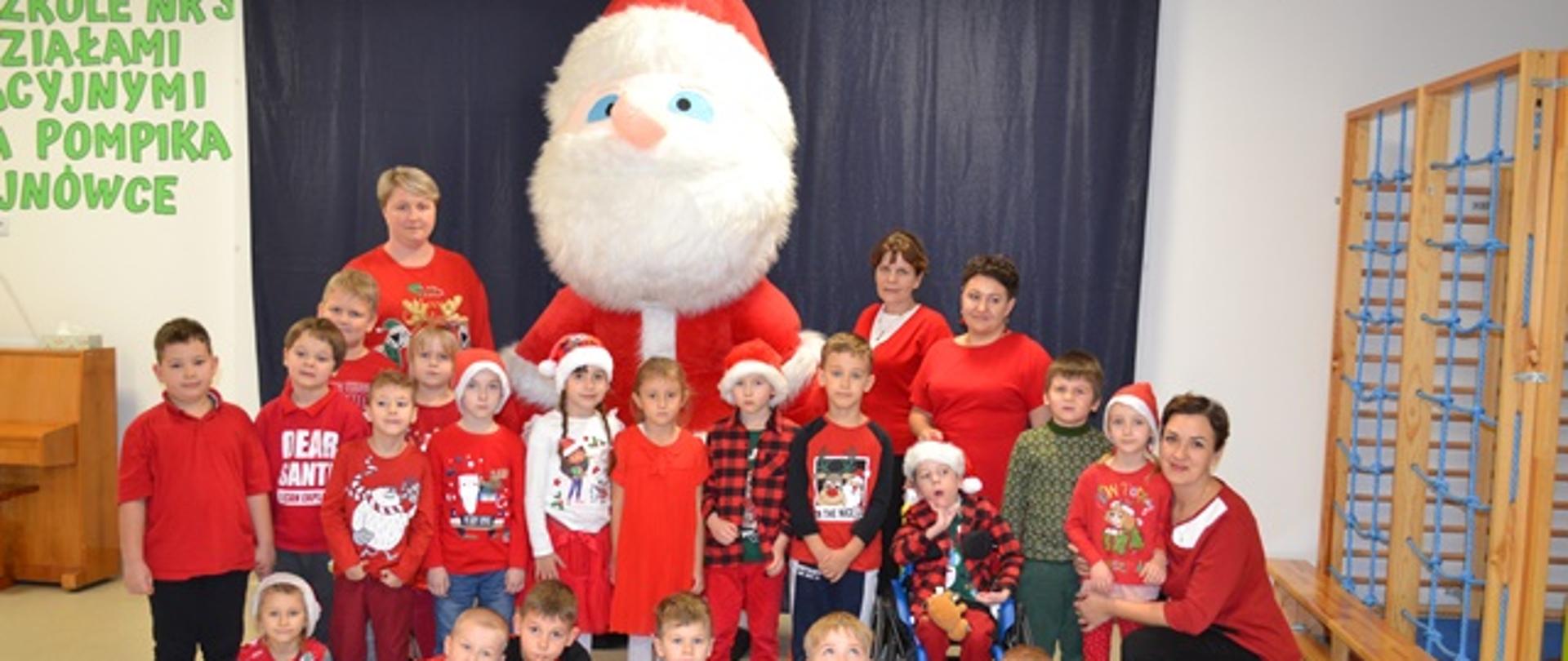 Dzieci pozują do wspólnego zdjęcia na tle dmuchanego Mikołaja