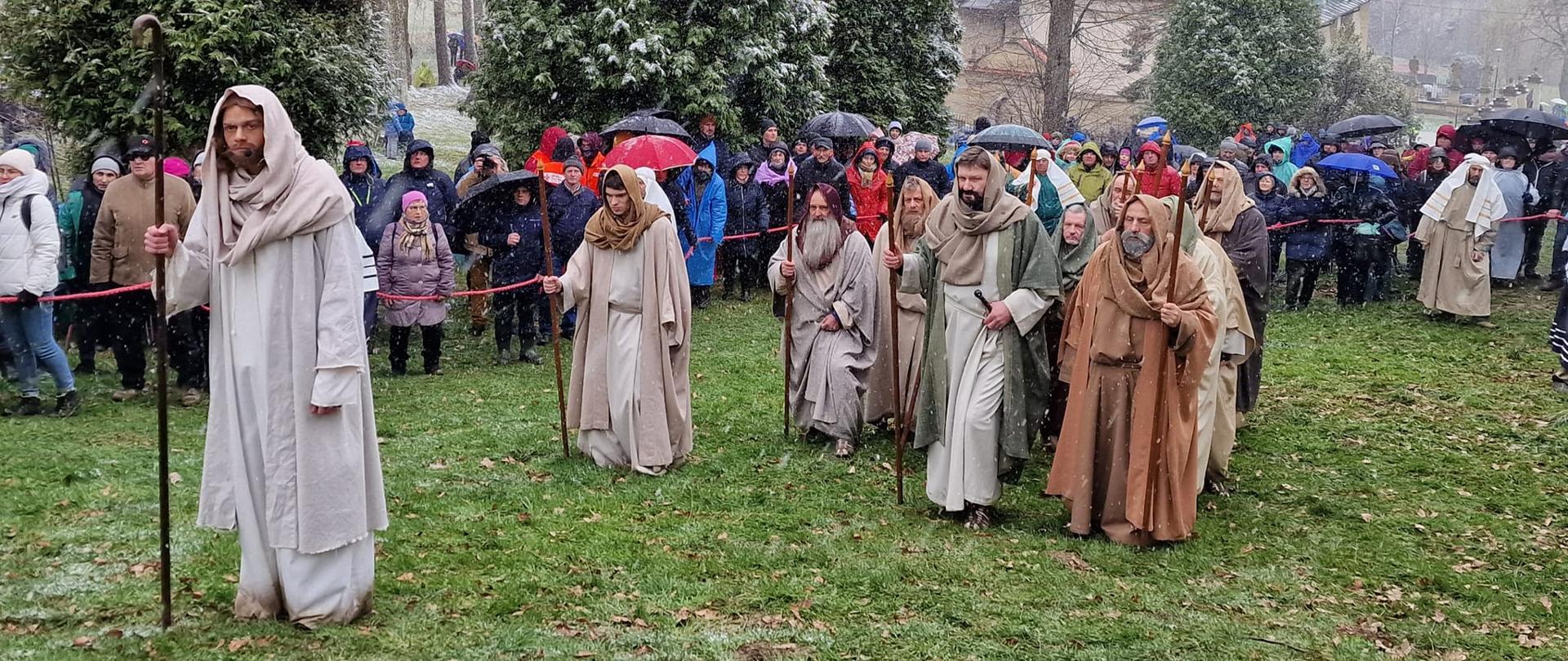 Misterium Męki Pańskiej w Kalwarii Zebrzydowskiej. Aktor odgrywający Jezusa wraz z Apostołami podąża w stronę Ogrodu Oliwnego. Aura pogodowa w śniegu i deszczu. 