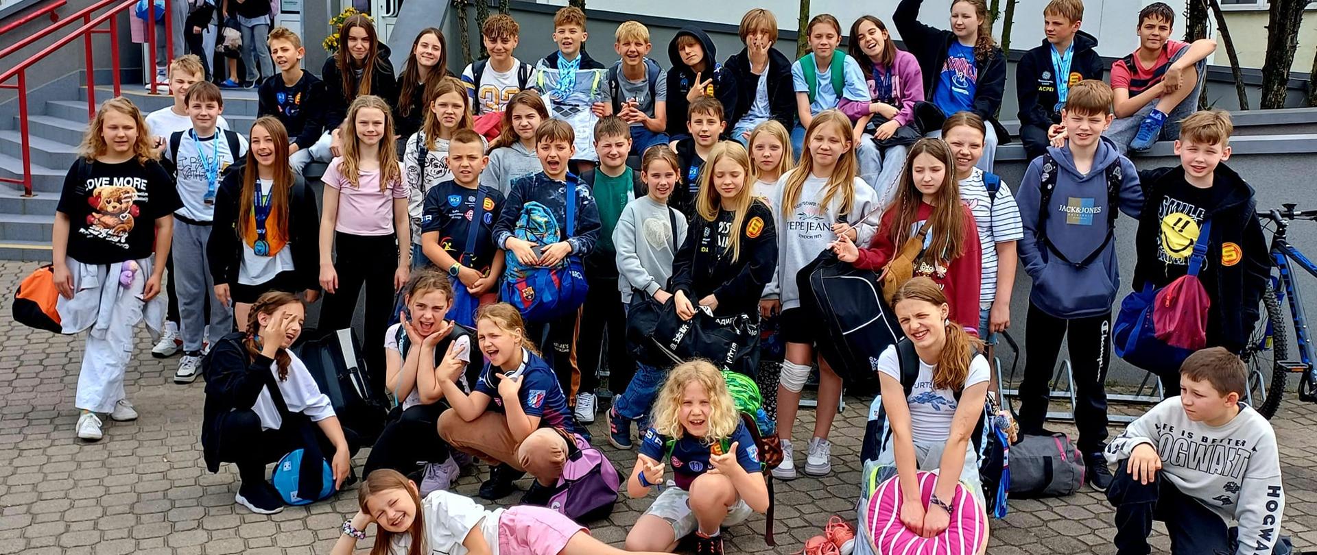 Zdjęcie grupowe młodzieży przed wejście na krytą pływalnię.