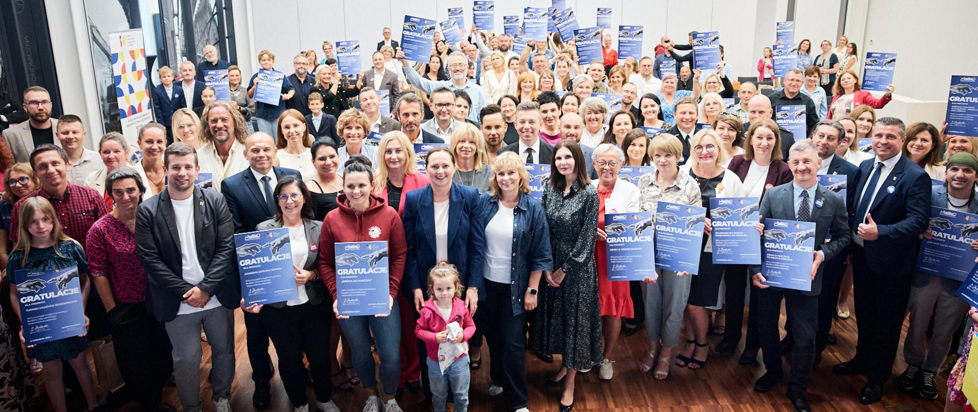 Zdjęcie grupowe osób trzymających dyplomy.