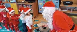 Mężczyzna w przebraniu św. Mikołaja rozmawia z dziećmi, rozdaje im prezenty