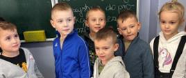 Dzieci stoją przy tablicy w klasie