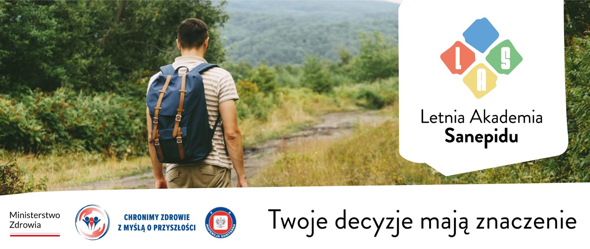 Mężczyzna spaceruje ścieżką wokół lasy i zieleń.
