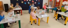 Dzieci siedzą przy stołach, rozwiązują zadania - układanie puzzli