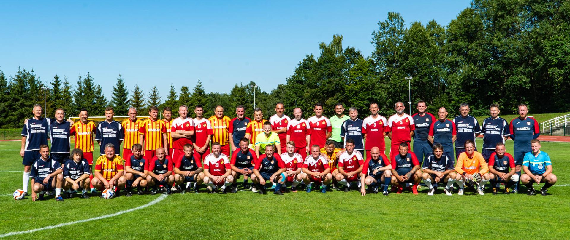 Grupa mężczyzn piłkarzy, na zielonej murawie. 