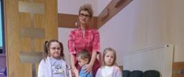 Dwie dziewczynki, chłopczyk i nauczycielka pozują do zdjęcia. 