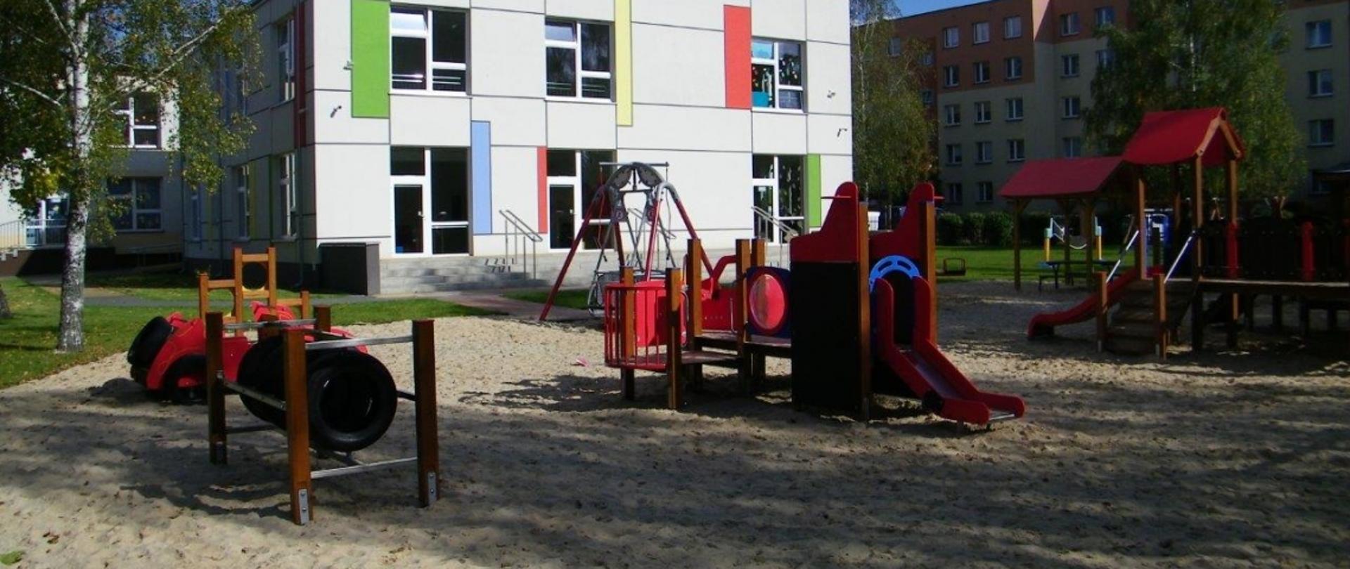 Plac zabaw, w tle nowy budynek przedszkola 