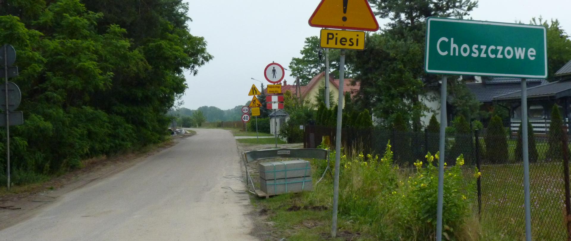 Droga asfaltowa. Na poboczu znak Choszczowe oraz uwaga piesi