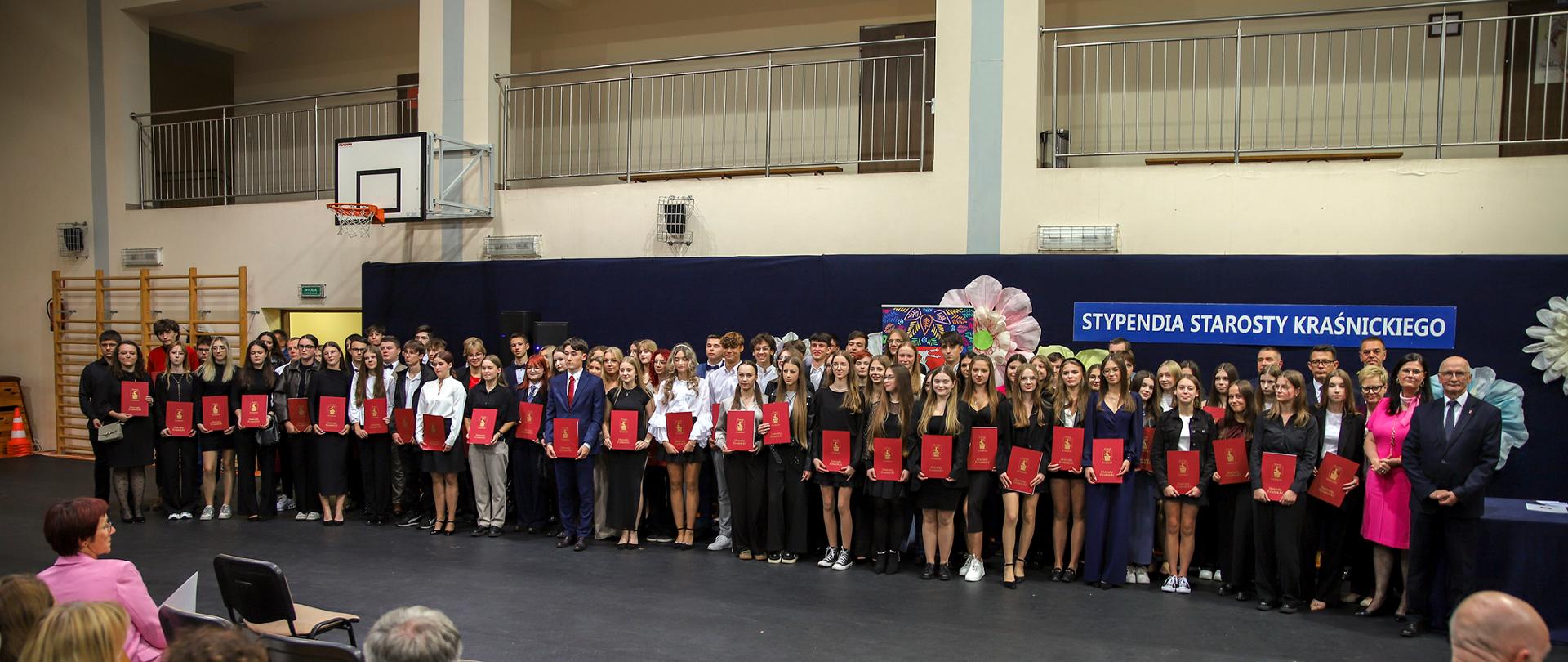 Zdjęcie przedstawia wszystkich nagrodzonych stypendystów na uroczystości wręczenia Stypendiów Starosty Kraśnickiego w hali sportowej w Zespole Szkół nr 2 w Kraśniku.
