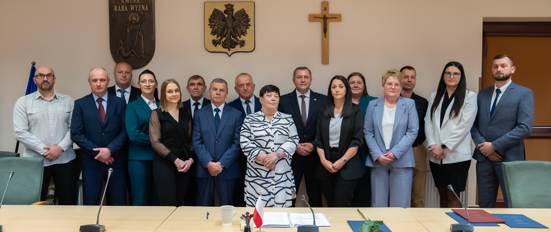 Zdjęcie przedstawia nowego Wójta pana Tomasza Rajce oraz nowo wybranych radnych pozujących do zdjęcia na sali obrad w urzędzie gminy podczas I sesja Rady Gminy 