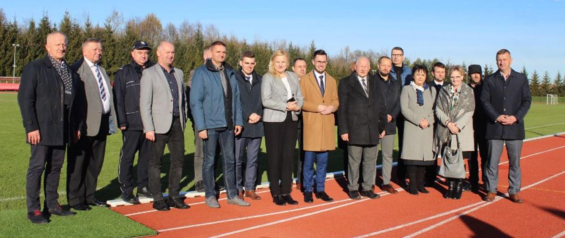 Zdjęcie grupowe na tle stadionu piłkarskiego. 