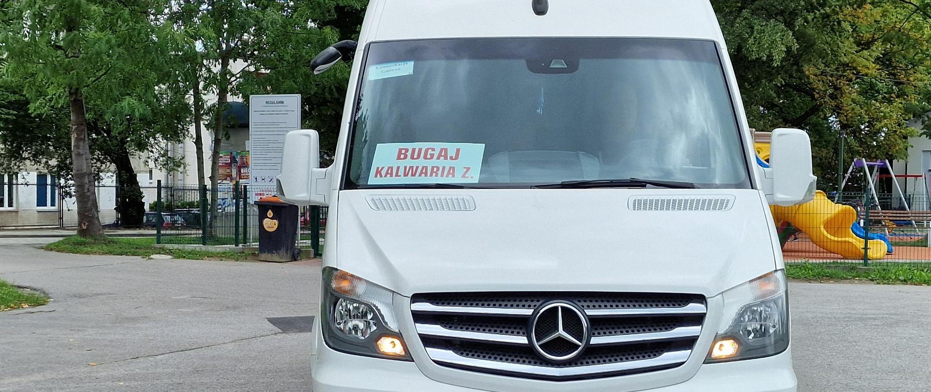 Biały bus marki Mercedes z tabliczką Bugaj Kalwaria Z. za przednią szybą 