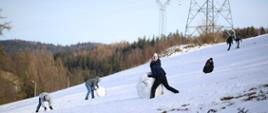 dzieci na polu turlają kule w celu połączeniach ich i zbudowaniu bałwana.